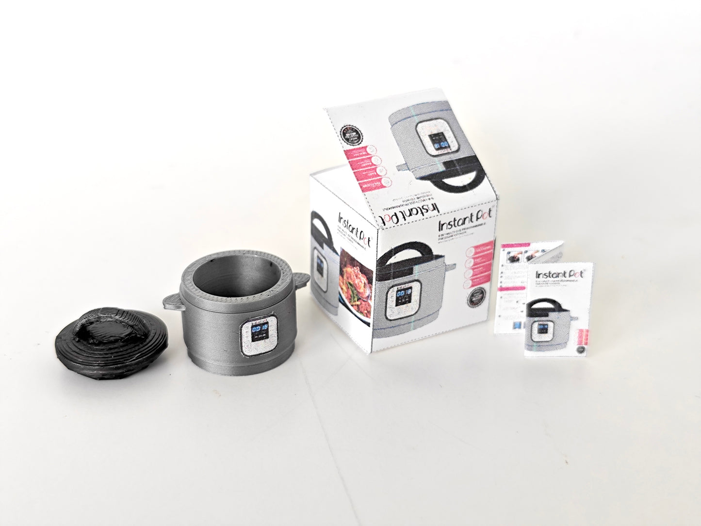 "A 3D-printable STL file of a 1:12 scale miniature Instant Pot, featuring detailed buttons and a lid for a realistic dollhouse kitchen appliance