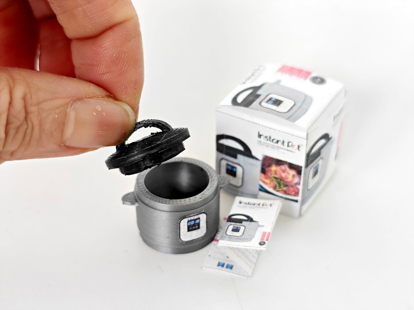 "A 3D-printable STL file of a 1:12 scale miniature Instant Pot, featuring detailed buttons and a lid for a realistic dollhouse kitchen appliance