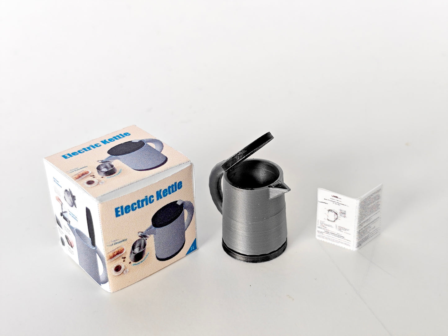 A 3D-printable STL file of a 1:12 scale miniature electric kettle with an openable lid, featuring detailed buttons and a spout for a realistic dollhouse kitchen.
