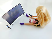 Overhead of blonde doll with popcorn and remote watching curved miniature TV.