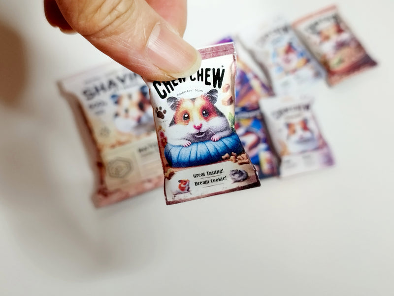 A digital preview of a printable 1:6 scale miniature template kit for dollhouse hamster pet accessories. The kit showcases 7 styles, including colorful hamster food bags, snack packets, wooden chip piles, and cozy pet bedding, arranged for a charming dollhouse pet scene.

