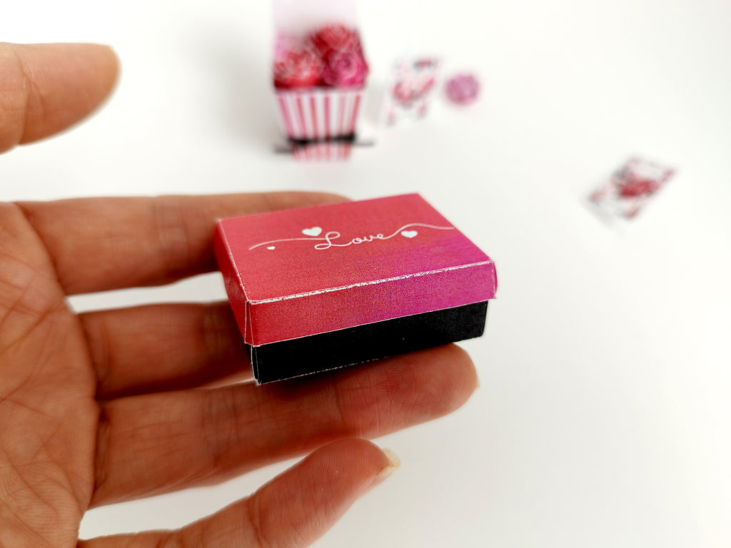 Miniature red and black 'Love' gift box held in a hand.