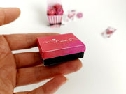 Miniature red and black 'Love' gift box held in a hand.