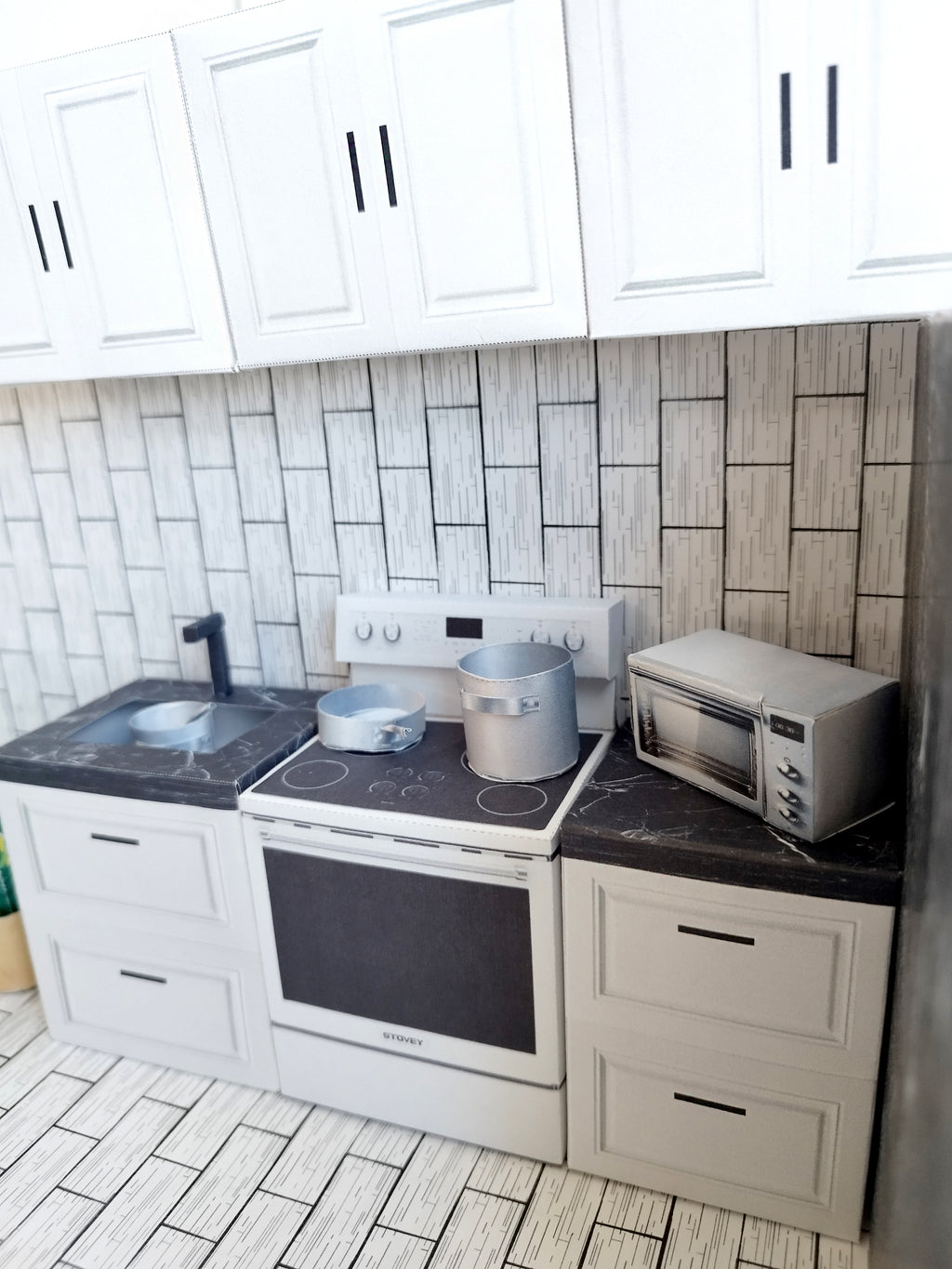 A digital printable template for a 1:12 scale dollhouse kitchen cabinet and drawer set, designed for BMM system dollhouse setups. The template features detailed, modern cabinets with drawers, ready to be printed on regular paper, cut, and assembled for a miniature kitchen scene.

