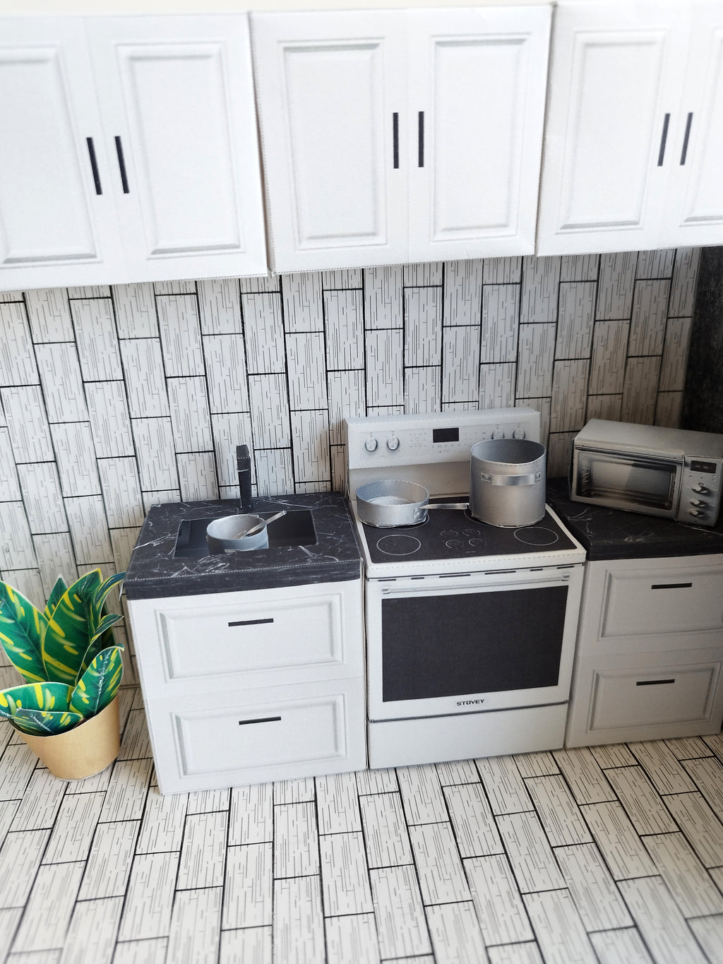 A digital printable template for a 1:12 scale dollhouse kitchen cabinet and drawer set, designed for BMM system dollhouse setups. The template features detailed, modern cabinets with drawers, ready to be printed on regular paper, cut, and assembled for a miniature kitchen scene.

