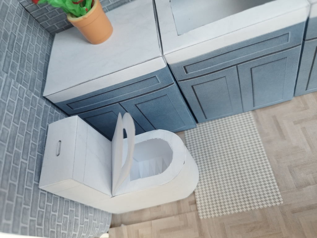 A digital printable template for a 1:12 scale dollhouse white toilet and matching carpet, designed for BMM shoe box bathroom scenes. The template includes a detailed, modern white toilet and a textured carpet, ready to be printed on regular paper, cut, and assembled for a miniature bathroom setting.

