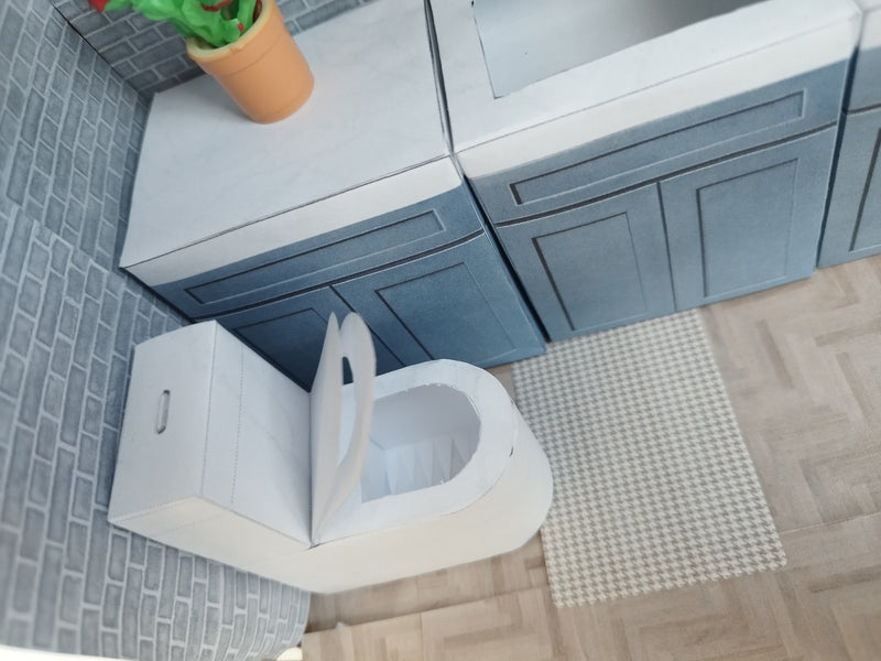 A digital printable template for a 1:12 scale dollhouse white toilet and matching carpet, designed for BMM shoe box bathroom scenes. The template includes a detailed, modern white toilet and a textured carpet, ready to be printed on regular paper, cut, and assembled for a miniature bathroom setting.

