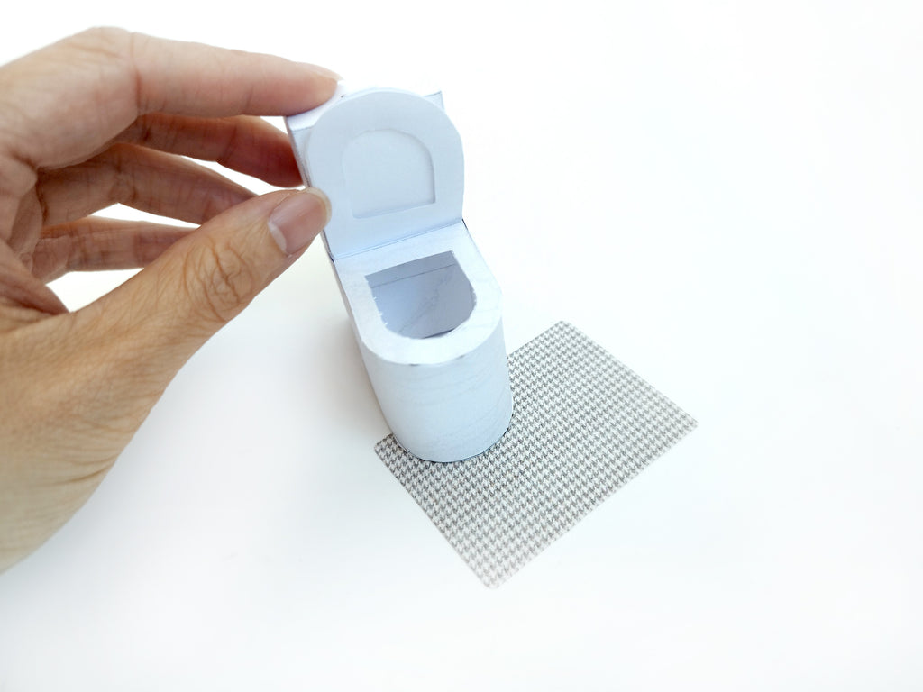 A digital printable template for a 1:12 scale dollhouse white toilet and matching carpet, designed for BMM shoe box bathroom scenes. The template includes a detailed, modern white toilet and a textured carpet, ready to be printed on regular paper, cut, and assembled for a miniature bathroom setting.

