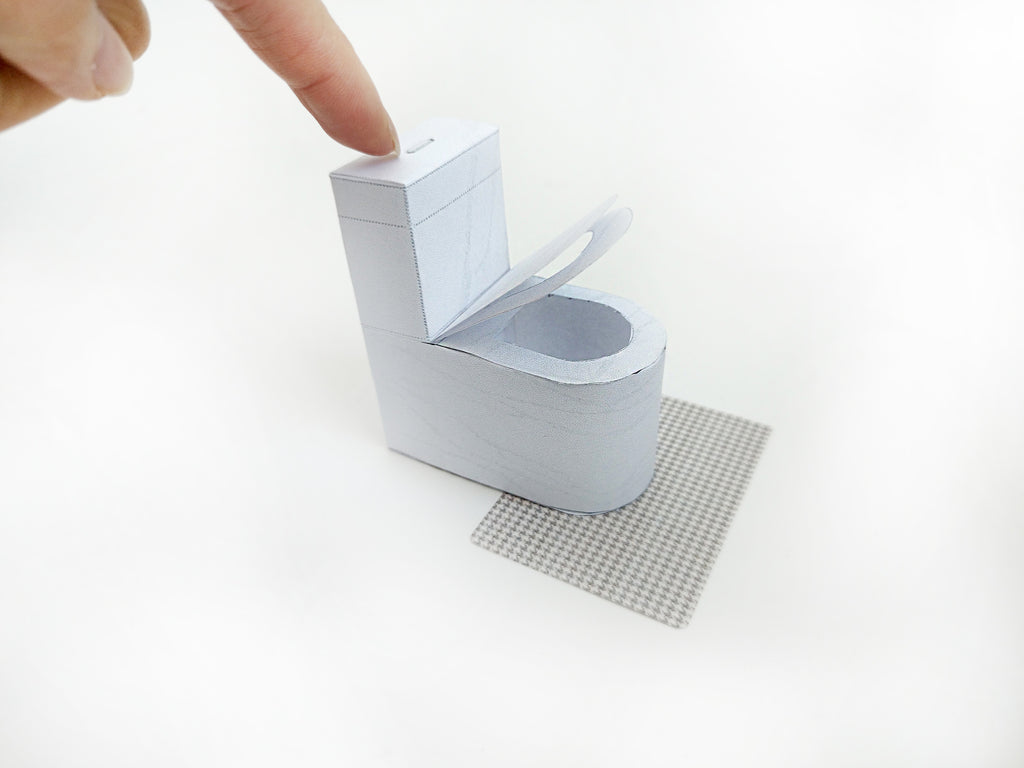 A digital printable template for a 1:12 scale dollhouse white toilet and matching carpet, designed for BMM shoe box bathroom scenes. The template includes a detailed, modern white toilet and a textured carpet, ready to be printed on regular paper, cut, and assembled for a miniature bathroom setting.

