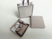 A 1:6 scale printable dollhouse set featuring four luxury brand-inspired brown shopping bags, a purse, and boxes, designed for department store or luxury home decor dioramas, ideal as yearly ornaments for miniature scenes.