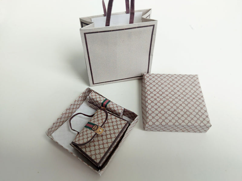 A 1:6 scale printable dollhouse set featuring four luxury brand-inspired brown shopping bags, a purse, and boxes, designed for department store or luxury home decor dioramas, ideal as yearly ornaments for miniature scenes.