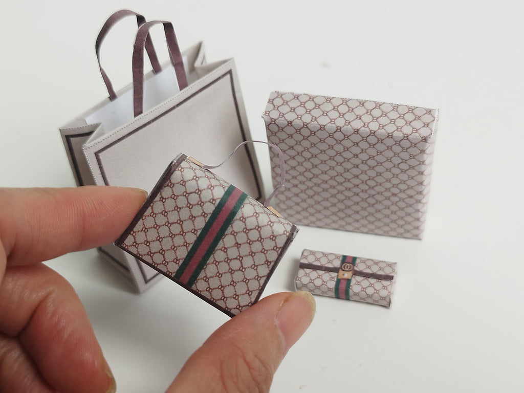 A 1:6 scale printable dollhouse set featuring four luxury brand-inspired brown shopping bags, a purse, and boxes, designed for department store or luxury home decor dioramas, ideal as yearly ornaments for miniature scenes.