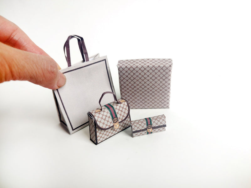 A 1:6 scale printable dollhouse set featuring four luxury brand-inspired brown shopping bags, a purse, and boxes, designed for department store or luxury home decor dioramas, ideal as yearly ornaments for miniature scenes.