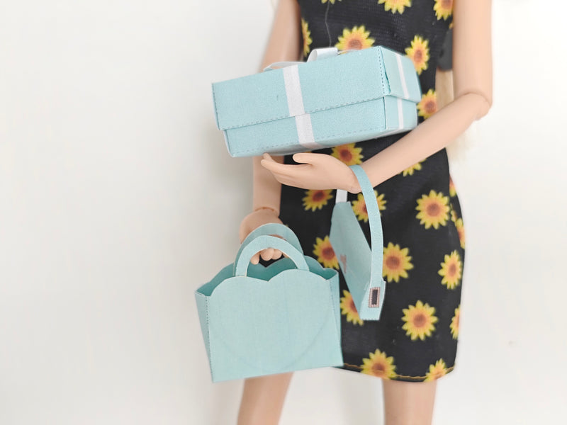 Enhance your dollhouse or department store with this 1:6 scale 5-item Sea Blue Purse and Gift Box set in black and sea blue tones. Ideal as a yearly ornament, perfect for stylish miniature displays and collectors