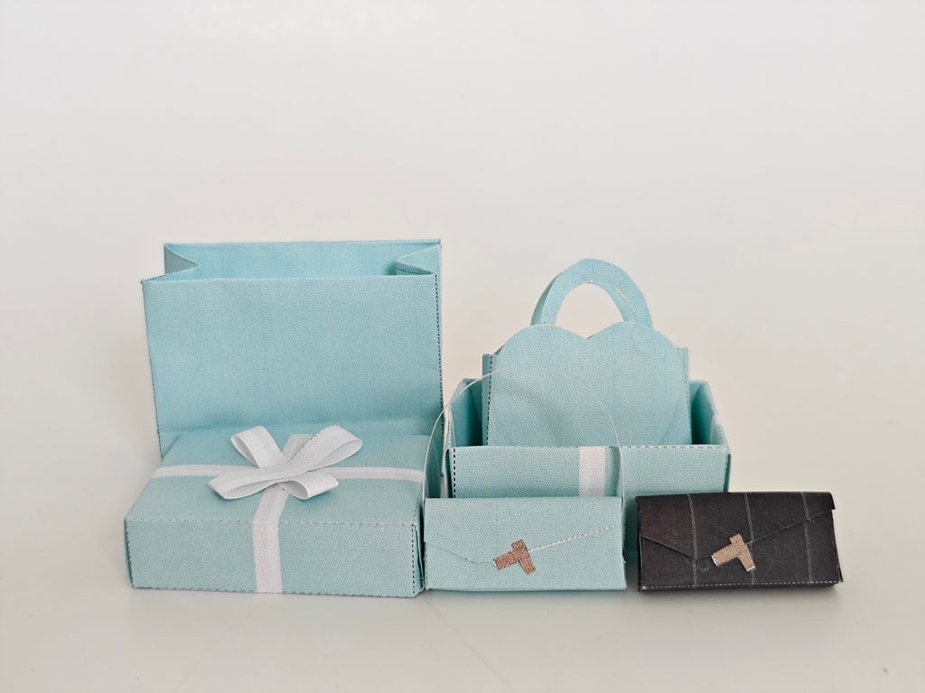 Enhance your dollhouse or department store with this 1:6 scale 5-item Sea Blue Purse and Gift Box set in black and sea blue tones. Ideal as a yearly ornament, perfect for stylish miniature displays and collectors