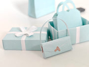 Enhance your dollhouse or department store with this 1:6 scale 5-item Sea Blue Purse and Gift Box set in black and sea blue tones. Ideal as a yearly ornament, perfect for stylish miniature displays and collectors
