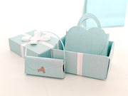 Enhance your dollhouse or department store with this 1:6 scale 5-item Sea Blue Purse and Gift Box set in black and sea blue tones. Ideal as a yearly ornament, perfect for stylish miniature displays and collectors