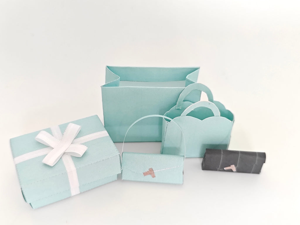 Enhance your dollhouse or department store with this 1:6 scale 5-item Sea Blue Purse and Gift Box set in black and sea blue tones. Ideal as a yearly ornament, perfect for stylish miniature displays and collectors