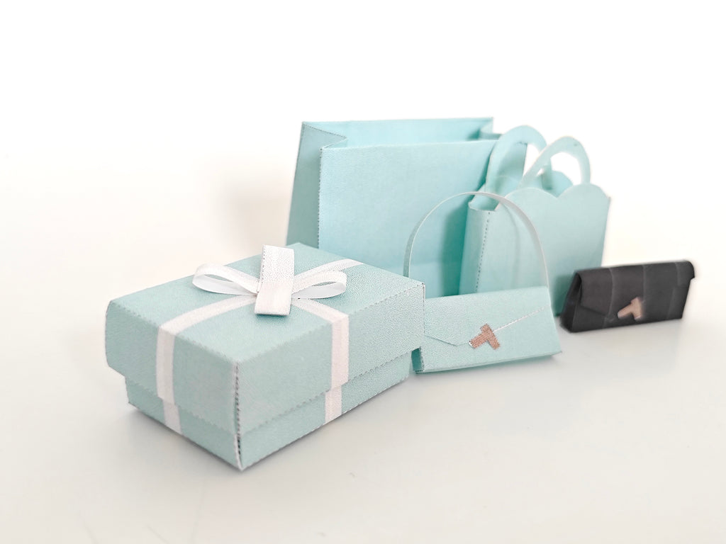 Enhance your dollhouse or department store with this 1:6 scale 5-item Sea Blue Purse and Gift Box set in black and sea blue tones. Ideal as a yearly ornament, perfect for stylish miniature displays and collectors