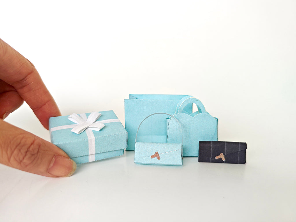 Enhance your dollhouse or department store with this 1:6 scale 5-item Sea Blue Purse and Gift Box set in black and sea blue tones. Ideal as a yearly ornament, perfect for stylish miniature displays and collectors