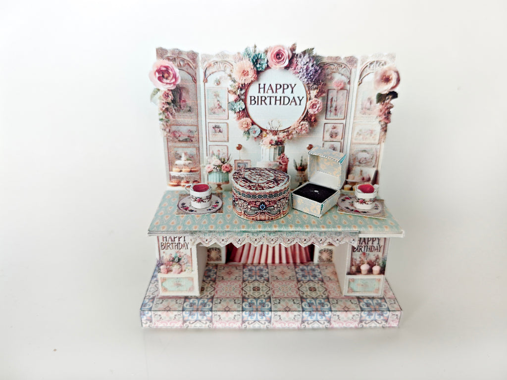 A 3D-printable STL file of a 1:12 scale vintage birthday stand DIY kit, featuring a detailed stand for displaying miniature birthday presents and cards in a dollhouse.