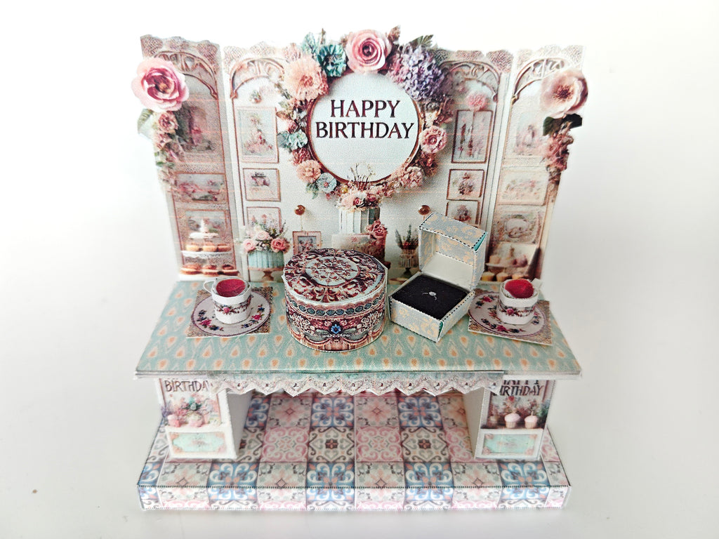 A 3D-printable STL file of a 1:12 scale vintage birthday stand DIY kit, featuring a detailed stand for displaying miniature birthday presents and cards in a dollhouse.