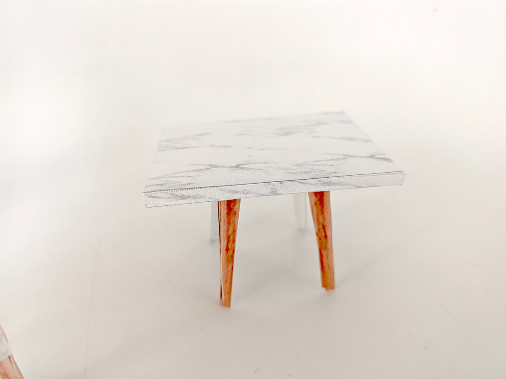 A 1:12 scale printable dollhouse furniture set from BMM Shoebox Miniature, featuring a dining table and chairs, crafted as DIY templates for a miniature living room or dining scene, ideal for diorama customization.