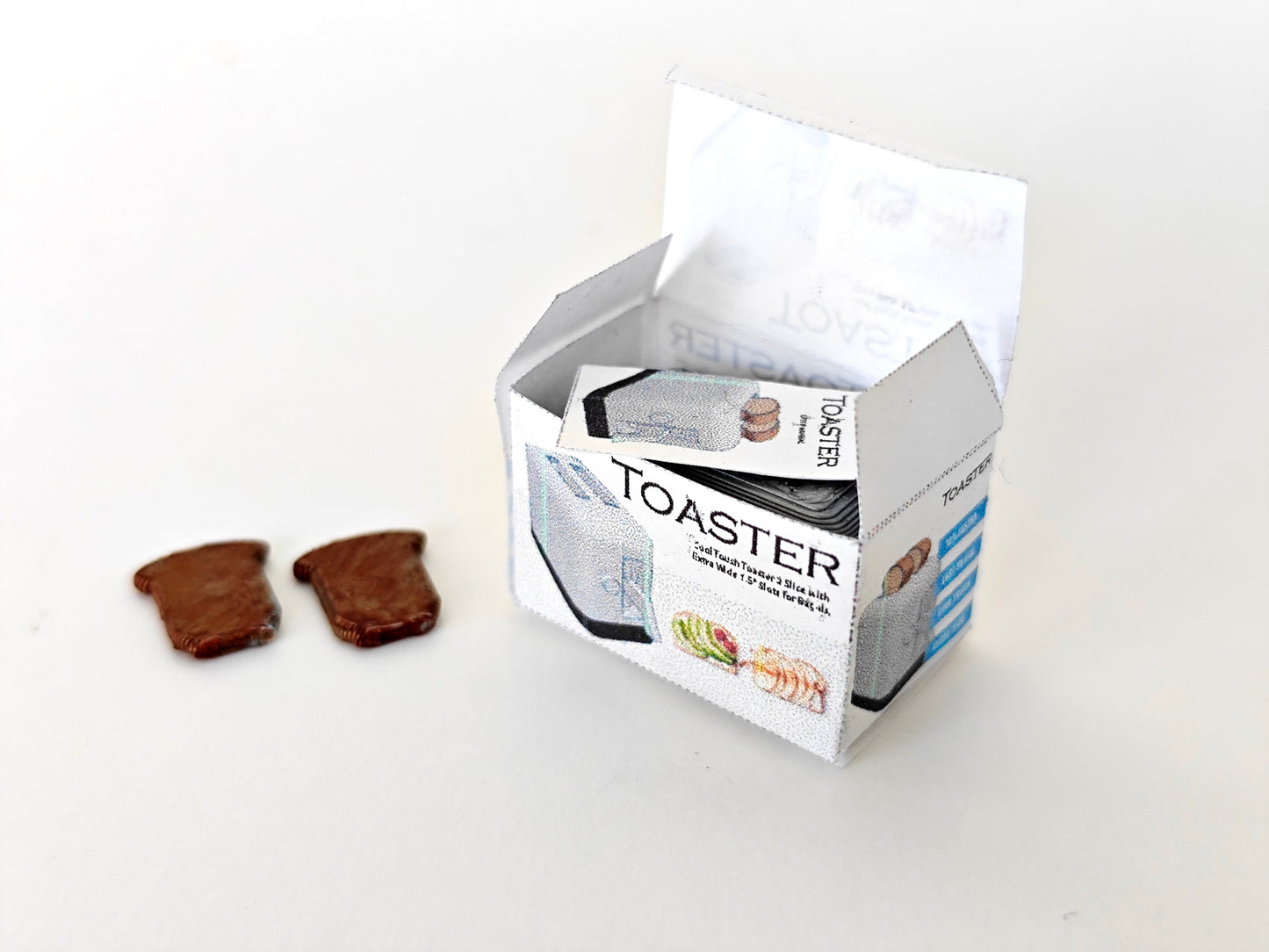 A 3D-printable STL file of a 1:12 scale miniature toaster, featuring detailed slots and buttons for a realistic dollhouse kitchen appliance