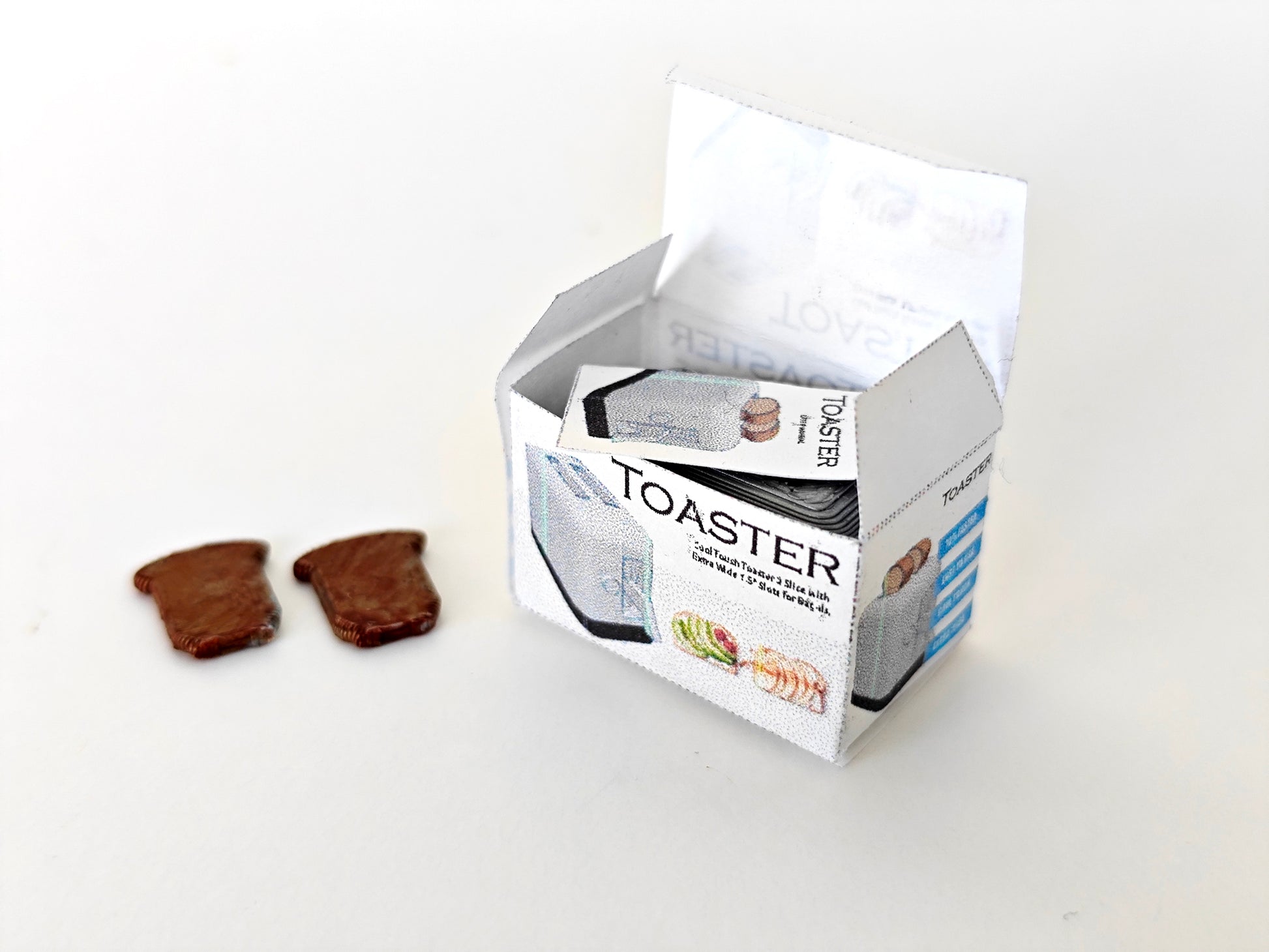 A 3D-printable STL file of a 1:12 scale miniature toaster, featuring detailed slots and buttons for a realistic dollhouse kitchen appliance