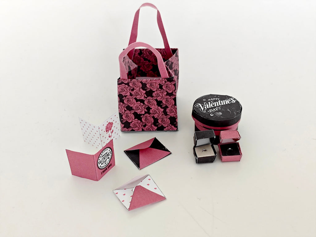 A 3D-printable STL file of a 1:6 scale Valentine’s Day gift set, featuring a flower gift box, romantic cards, rose bags, and an engagement ring, designed as charming dollhouse accessories for a miniature proposal scene or play scale display.
