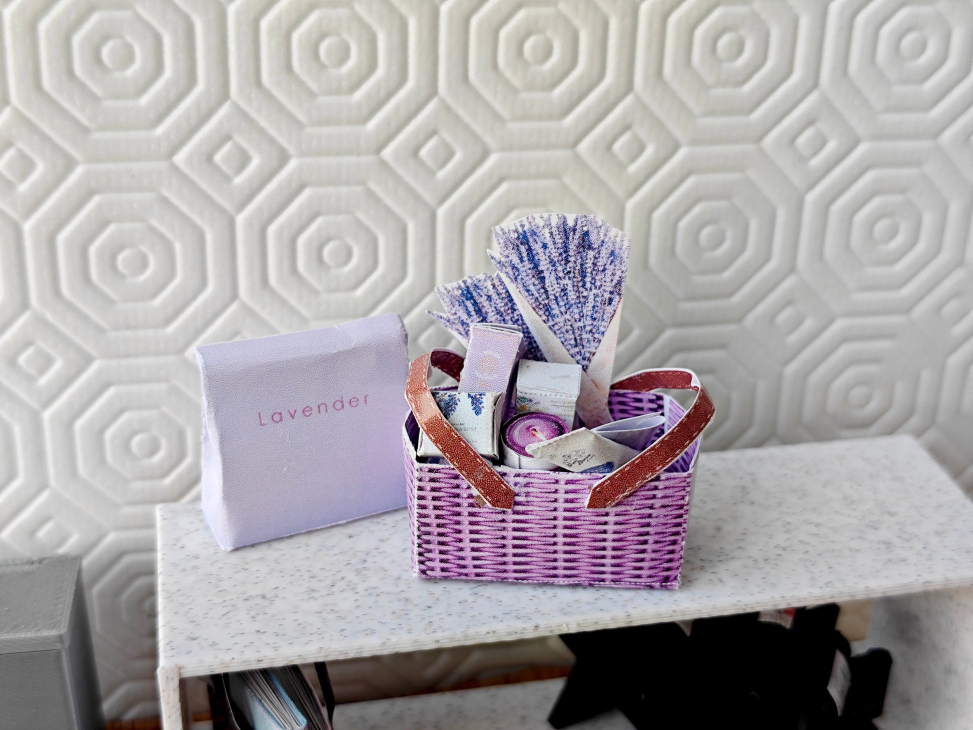 Discover our 1:12 scale lavender gift basket, a charming dollhouse hamper with 11 miniature items including teas, hand cream, soaps, scented fragrance bags, and candles—perfect for a tiny spa retreat