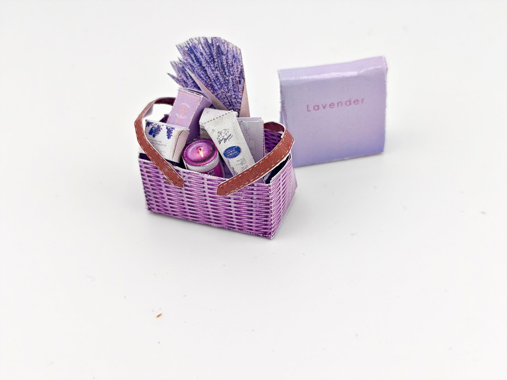 Discover our 1:12 scale lavender gift basket, a charming dollhouse hamper with 11 miniature items including teas, hand cream, soaps, scented fragrance bags, and candles—perfect for a tiny spa retreat