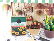 Discover the Garden Corner Miniature Stand: Create your own mini garden with plants, newspaper, potting mix, and pots. This miniature kit includes paper crafting supplies and a 7x5 frame for a charming, DIY display.