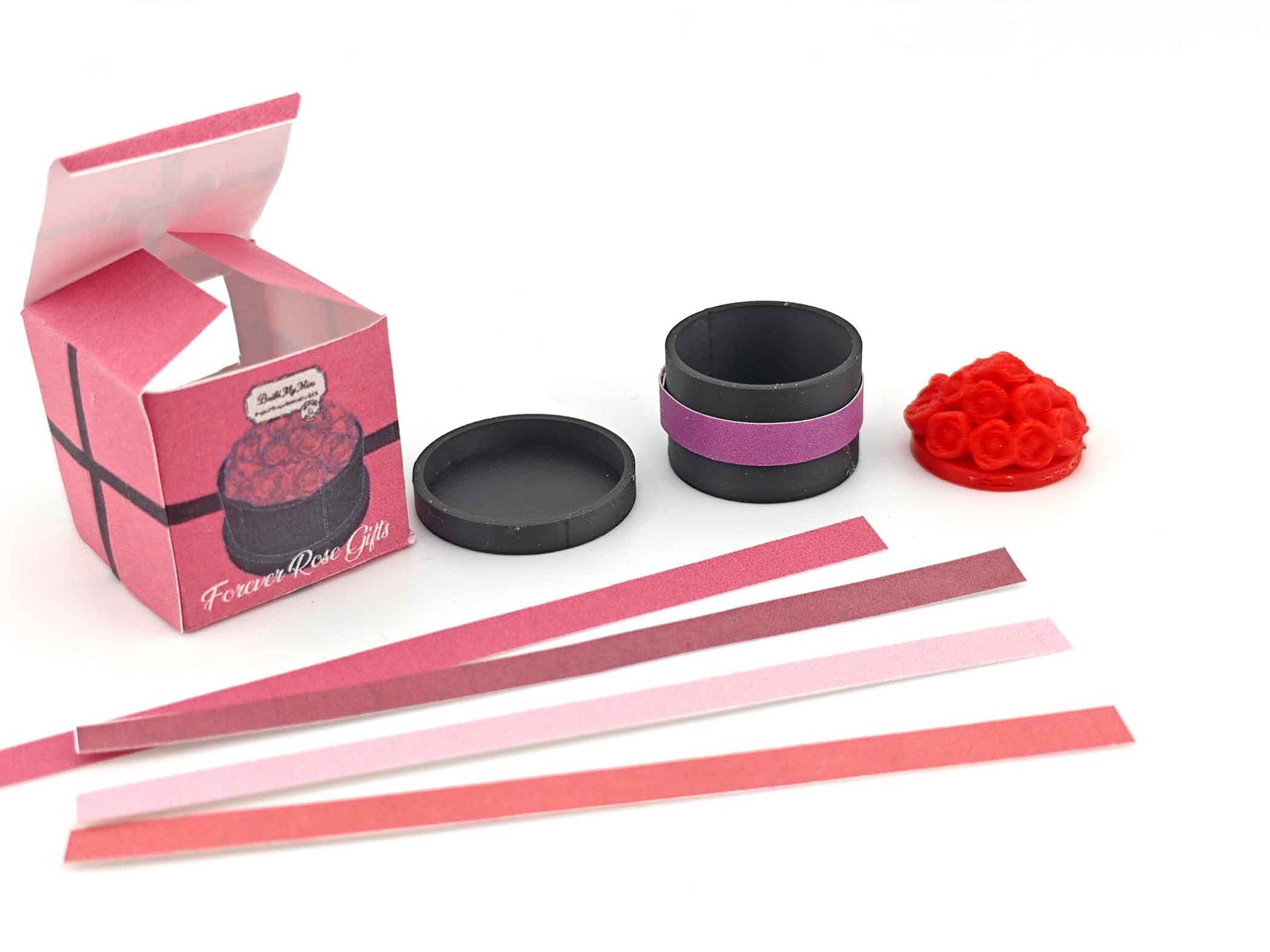 A digital rendering of a 3D printable miniature dollhouse flower box, featuring a rectangular wooden box with a grid pattern on the front. The box is accompanied by colorful strips in red, pink, and white, designed to slide into the grid for a customizable look, ideal for Mother's Day and Valentine's Day decor.