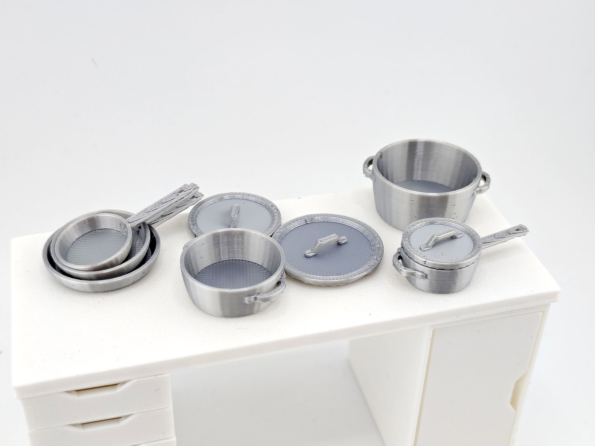 Complete your dollhouse kitchen with timeless cookware!
This 1:12 Miniature Pots and Pans Set includes six detailed 3D printable kitchen pieces — each with matching lids for an authentic look. Designed to fit perfectly in miniature kitchens and cooking dioramas, this set brings realistic charm to your PickScene culinary displays.
