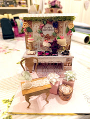 A 3D-printable STL file of a 1:12 scale vintage birthday stand DIY kit, featuring a detailed stand for displaying miniature birthday presents and cards in a dollhouse.